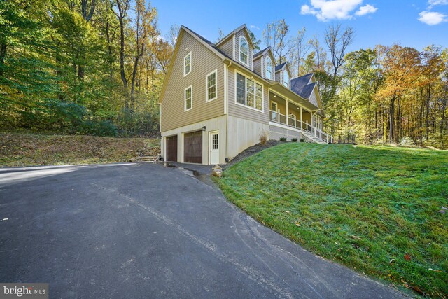 view of home's exterior with a porch, a yard, and a garage