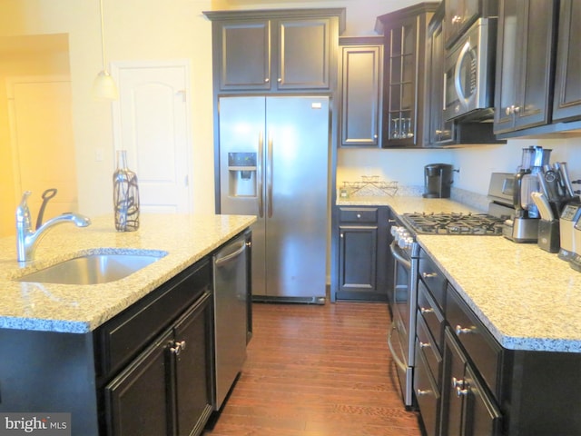 kitchen featuring sink, light stone counters, dark hardwood / wood-style flooring, pendant lighting, and appliances with stainless steel finishes