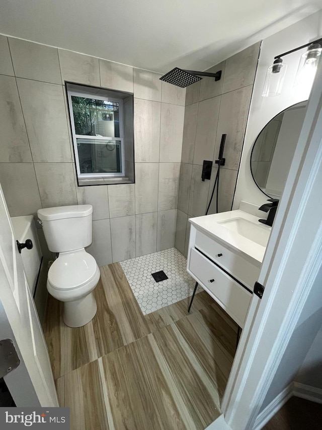 bathroom featuring walk in shower, vanity, toilet, and tile walls