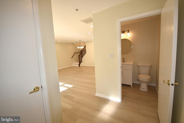 hallway featuring light hardwood / wood-style floors and an inviting chandelier