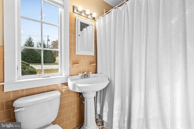 bathroom with tile walls and toilet