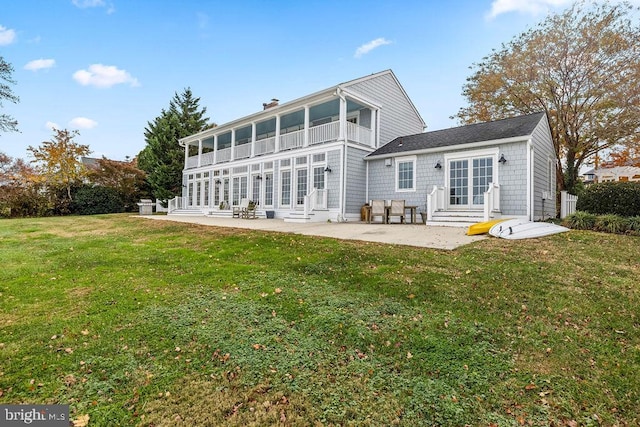 rear view of property with a sunroom, a lawn, and a patio