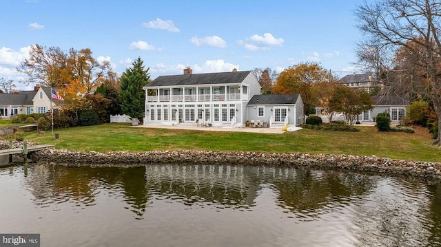 rear view of property featuring french doors, a yard, a water view, and a patio