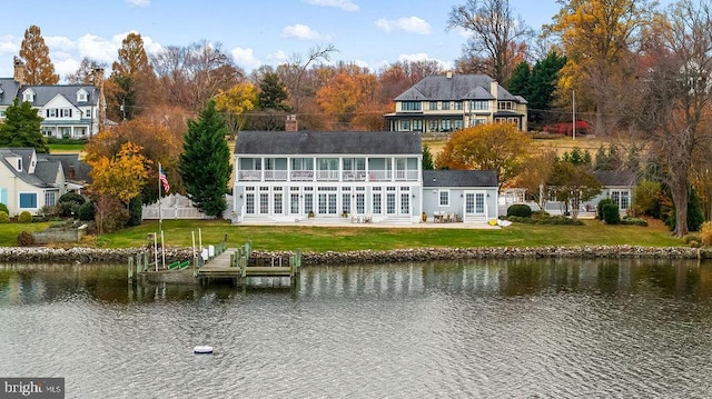 rear view of house with a water view and a yard