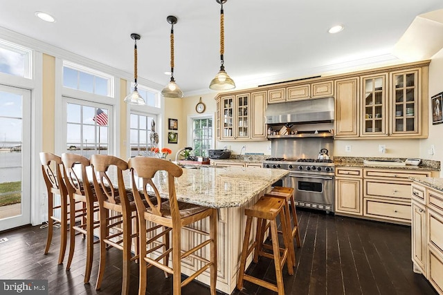 kitchen with extractor fan, double oven range, sink, hanging light fixtures, and a breakfast bar area