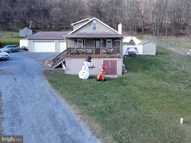 view of front of house with a front lawn, covered porch, a garage, and a storage unit