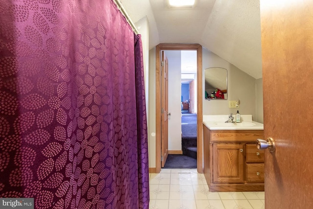 bathroom featuring a textured ceiling, vanity, and vaulted ceiling