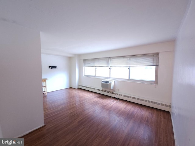 empty room featuring an AC wall unit, baseboard heating, and dark wood-type flooring