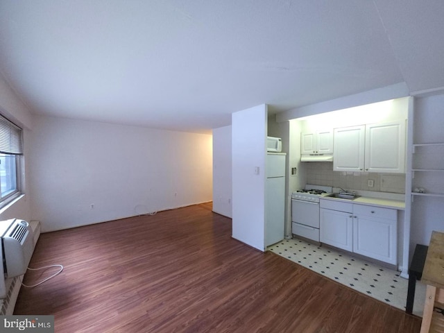 kitchen featuring white appliances, a wall mounted AC, decorative backsplash, white cabinets, and sink