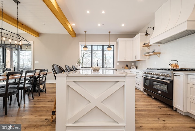 kitchen featuring white cabinetry, double oven range, decorative light fixtures, a kitchen bar, and custom exhaust hood