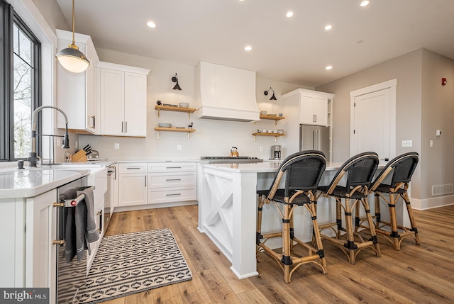 kitchen featuring light hardwood / wood-style floors, white cabinetry, a wealth of natural light, and custom exhaust hood