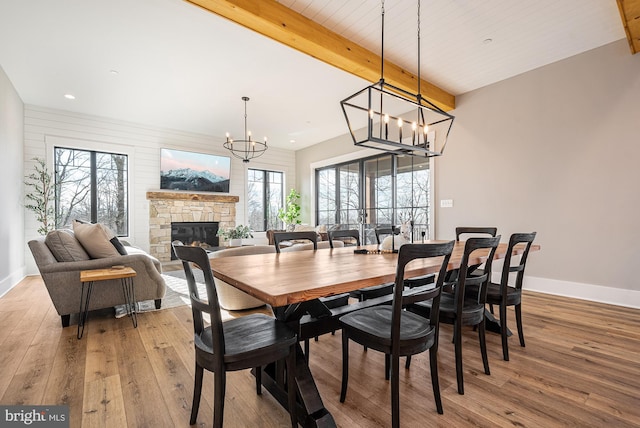 dining space featuring a stone fireplace, plenty of natural light, and light hardwood / wood-style floors