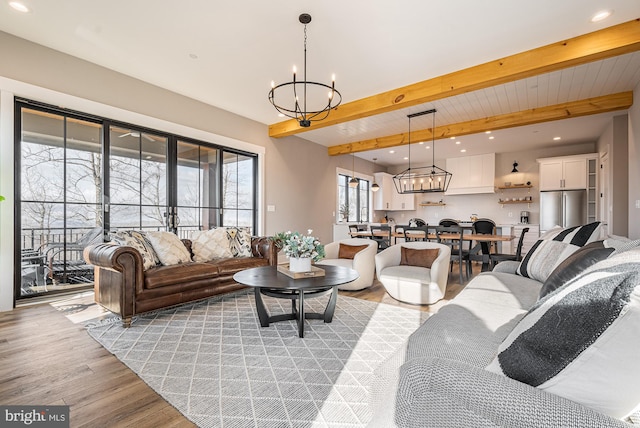 living room featuring beam ceiling, french doors, an inviting chandelier, and light wood-type flooring