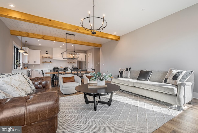 living room with beam ceiling, light hardwood / wood-style flooring, and a chandelier