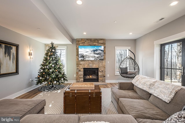 living room featuring hardwood / wood-style flooring, a healthy amount of sunlight, and a stone fireplace