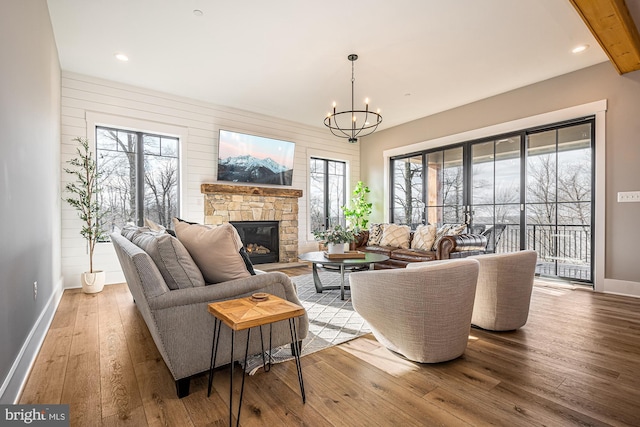 living room featuring a fireplace, light hardwood / wood-style flooring, a healthy amount of sunlight, and a notable chandelier