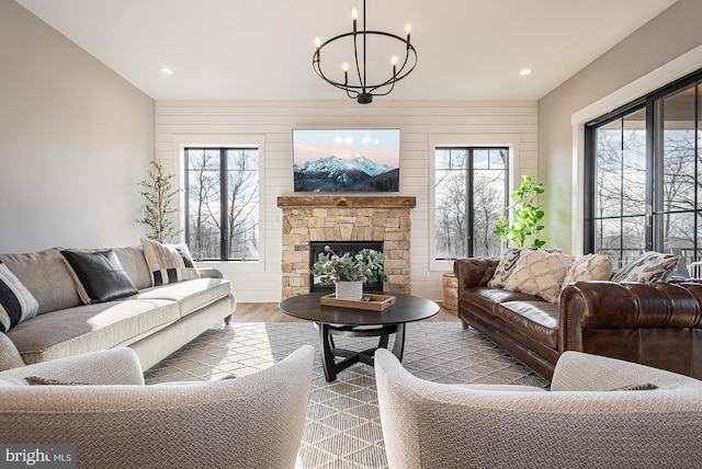 living room featuring a fireplace, hardwood / wood-style flooring, a wealth of natural light, and a notable chandelier