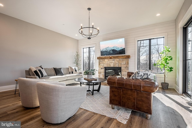 living room with a fireplace, plenty of natural light, an inviting chandelier, and hardwood / wood-style flooring