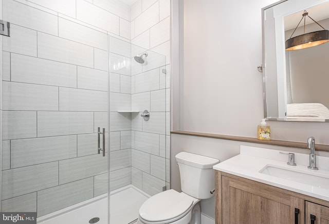 bathroom featuring a shower with door, vanity, and toilet