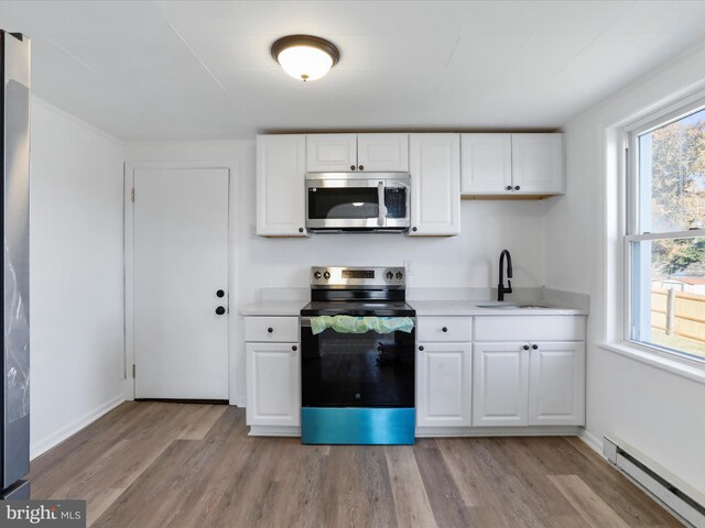 kitchen with white cabinetry, sink, stainless steel appliances, baseboard heating, and light wood-type flooring