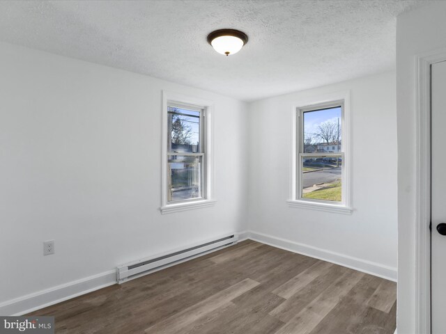 empty room featuring a textured ceiling, a baseboard radiator, and hardwood / wood-style flooring