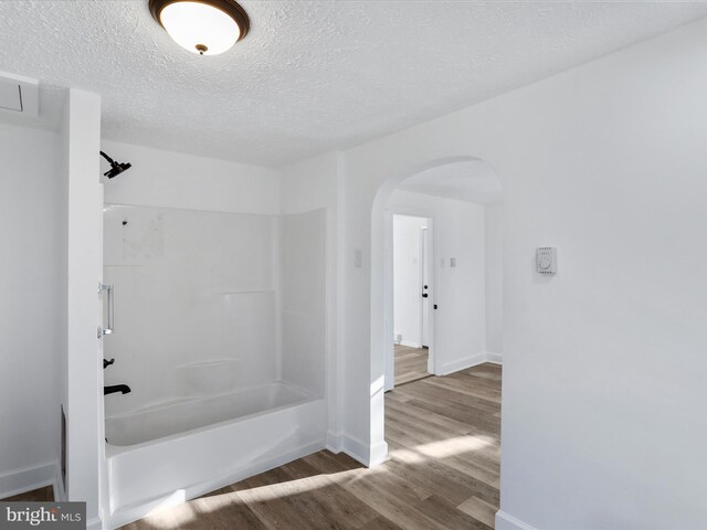 bathroom with bathing tub / shower combination, a textured ceiling, and hardwood / wood-style flooring