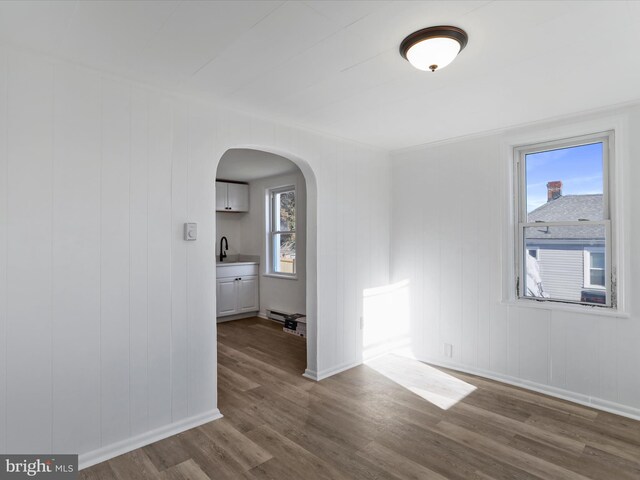 spare room featuring hardwood / wood-style floors, wood walls, sink, and a baseboard heating unit