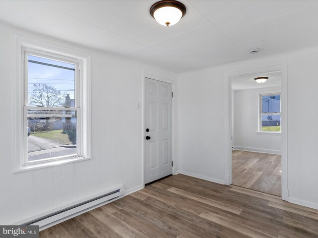 foyer with hardwood / wood-style floors, a healthy amount of sunlight, and a baseboard heating unit