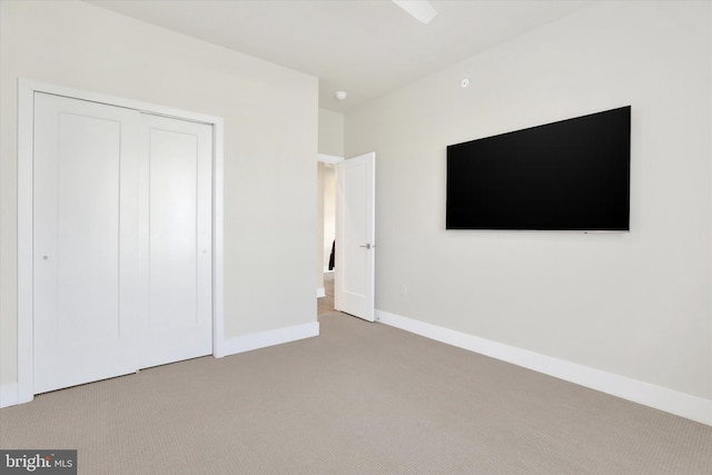 unfurnished bedroom featuring light colored carpet and a closet