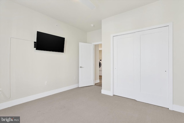 unfurnished bedroom with light carpet, washer / clothes dryer, and a closet