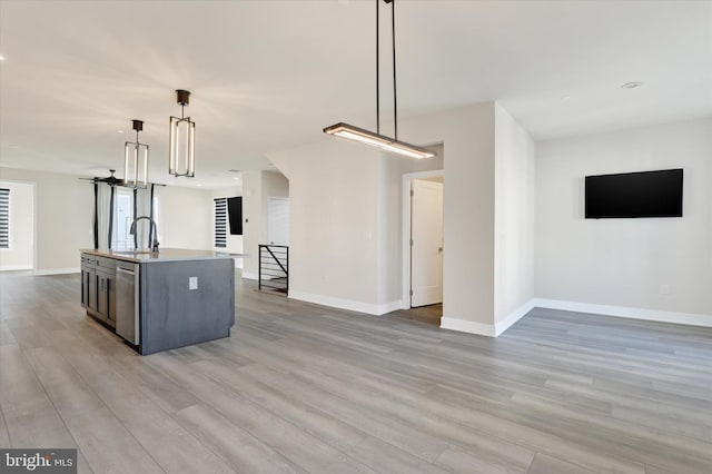 kitchen with dishwasher, pendant lighting, light wood-type flooring, and a center island with sink