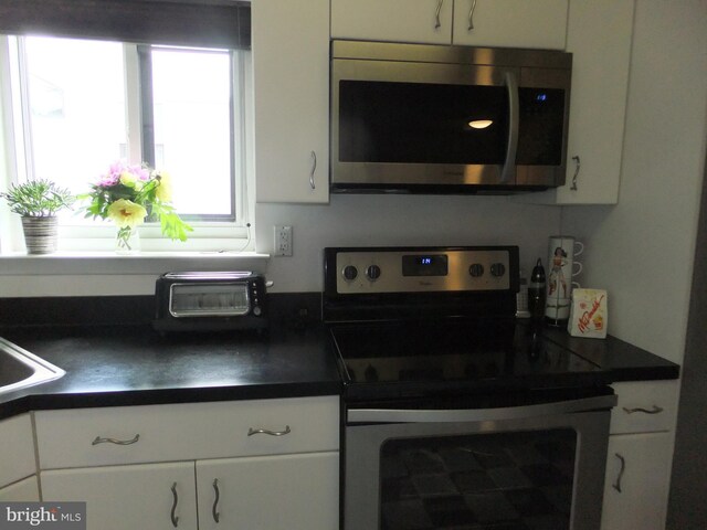 1710 Oakwood Ter Unit 3E, Penn Valley, PA 19072 - kitchen with appliances with stainless steel finishes, dark countertops, and white cabinets