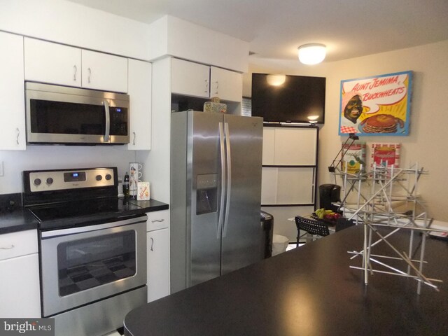 1710 Oakwood Ter Unit 3E, Penn Valley, PA 19072 - kitchen featuring appliances with stainless steel finishes, dark countertops, and white cabinetry