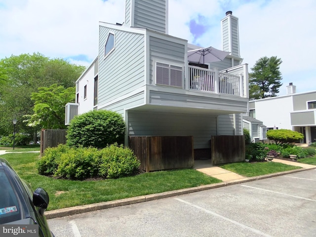 view of home's exterior featuring a balcony and a yard