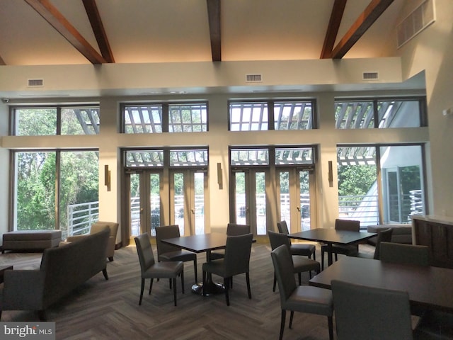 dining space with beamed ceiling, a wealth of natural light, a high ceiling, and french doors