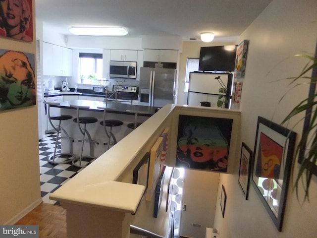 kitchen featuring white cabinets, a breakfast bar, and appliances with stainless steel finishes