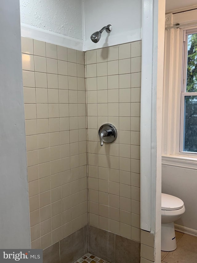 bathroom with a tile shower, tile patterned floors, and toilet