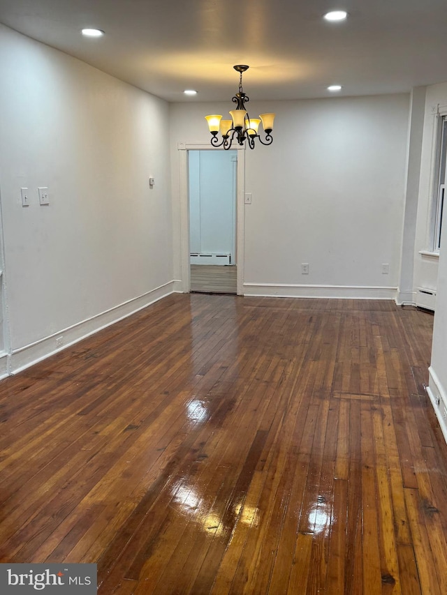 unfurnished dining area featuring dark hardwood / wood-style flooring, a baseboard radiator, and an inviting chandelier