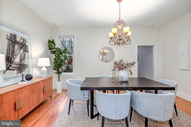 dining area featuring light wood-type flooring and a notable chandelier