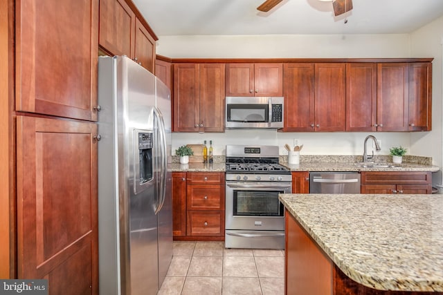 kitchen with light stone countertops, sink, ceiling fan, stainless steel appliances, and light tile patterned floors