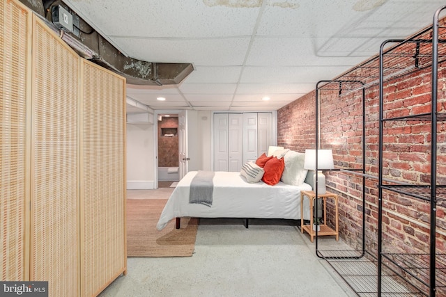 bedroom with a paneled ceiling and brick wall