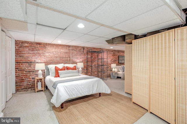 bedroom with a drop ceiling and brick wall