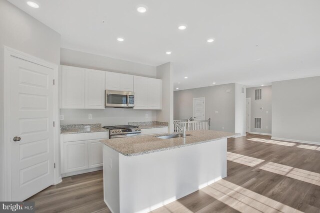 kitchen featuring stainless steel appliances, a kitchen island with sink, sink, light hardwood / wood-style flooring, and white cabinetry