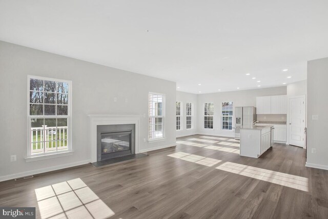 unfurnished living room with plenty of natural light, dark hardwood / wood-style floors, and sink