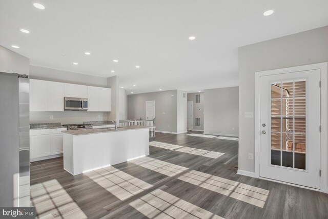 kitchen with dark hardwood / wood-style floors, sink, white cabinetry, and an island with sink