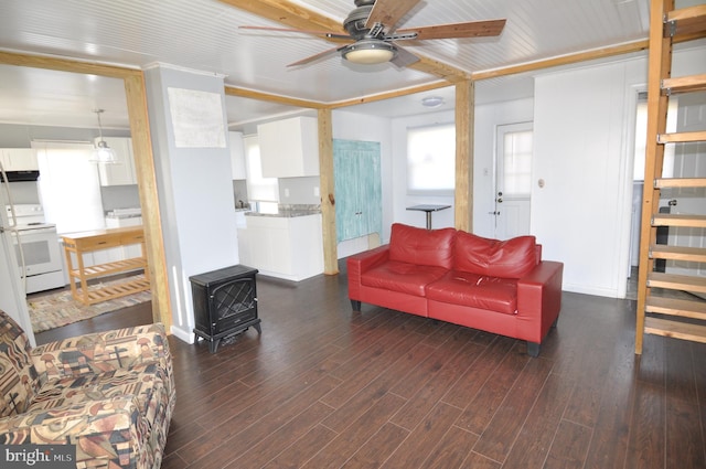 living room with a wood stove, ceiling fan, and dark wood-type flooring