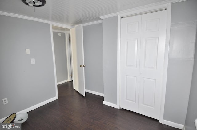 unfurnished bedroom with ornamental molding, a closet, and dark wood-type flooring