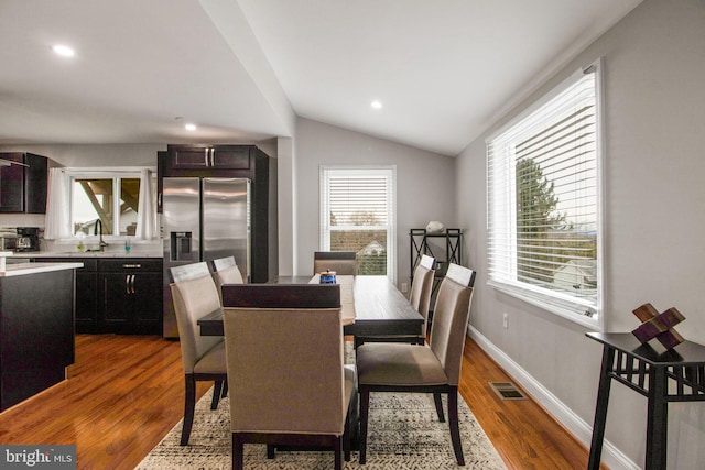 dining space with sink, vaulted ceiling, and hardwood / wood-style flooring