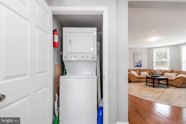 laundry room with stacked washing maching and dryer and wood-type flooring