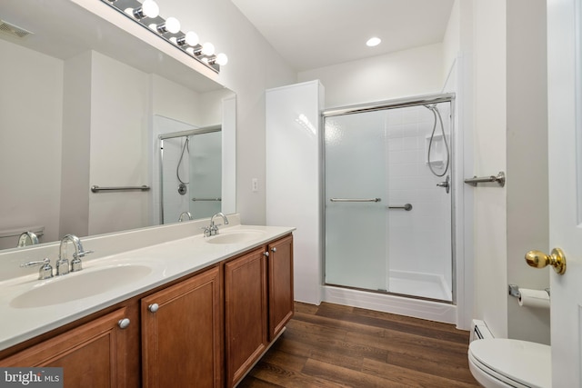 bathroom with an enclosed shower, vanity, a baseboard heating unit, hardwood / wood-style flooring, and toilet